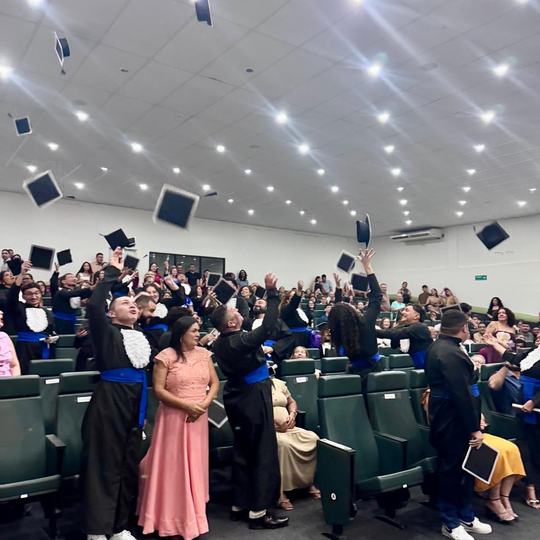 Imagem com estudantes e padrinhos, os capelos dos formados estão no ar