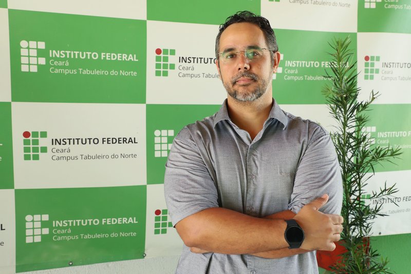 Imagem do novo diretor-geral do campus Tabuleiro do Norte, com os braços cruzados, usando camisa social de cor cinza.